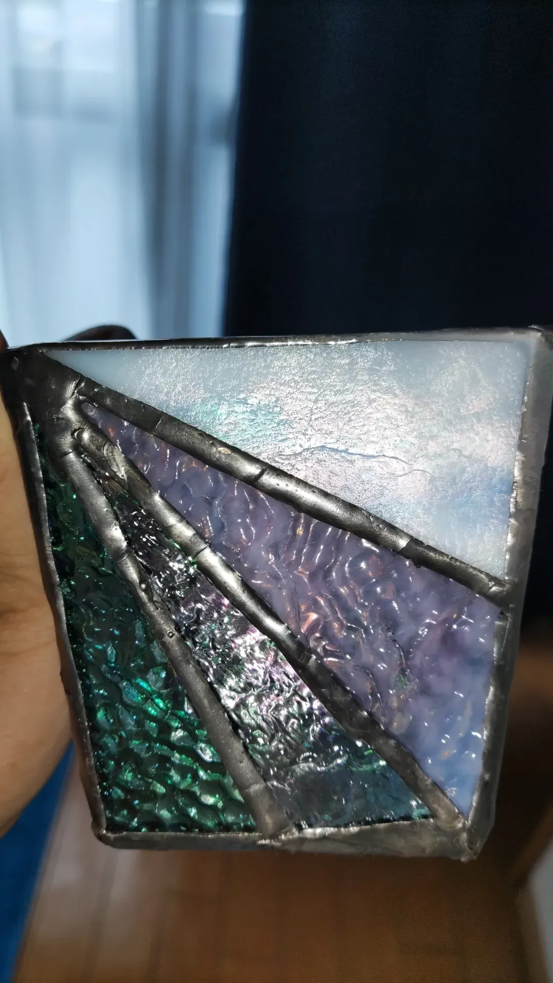 Small stained-glass volume held in hand, iridescent glass