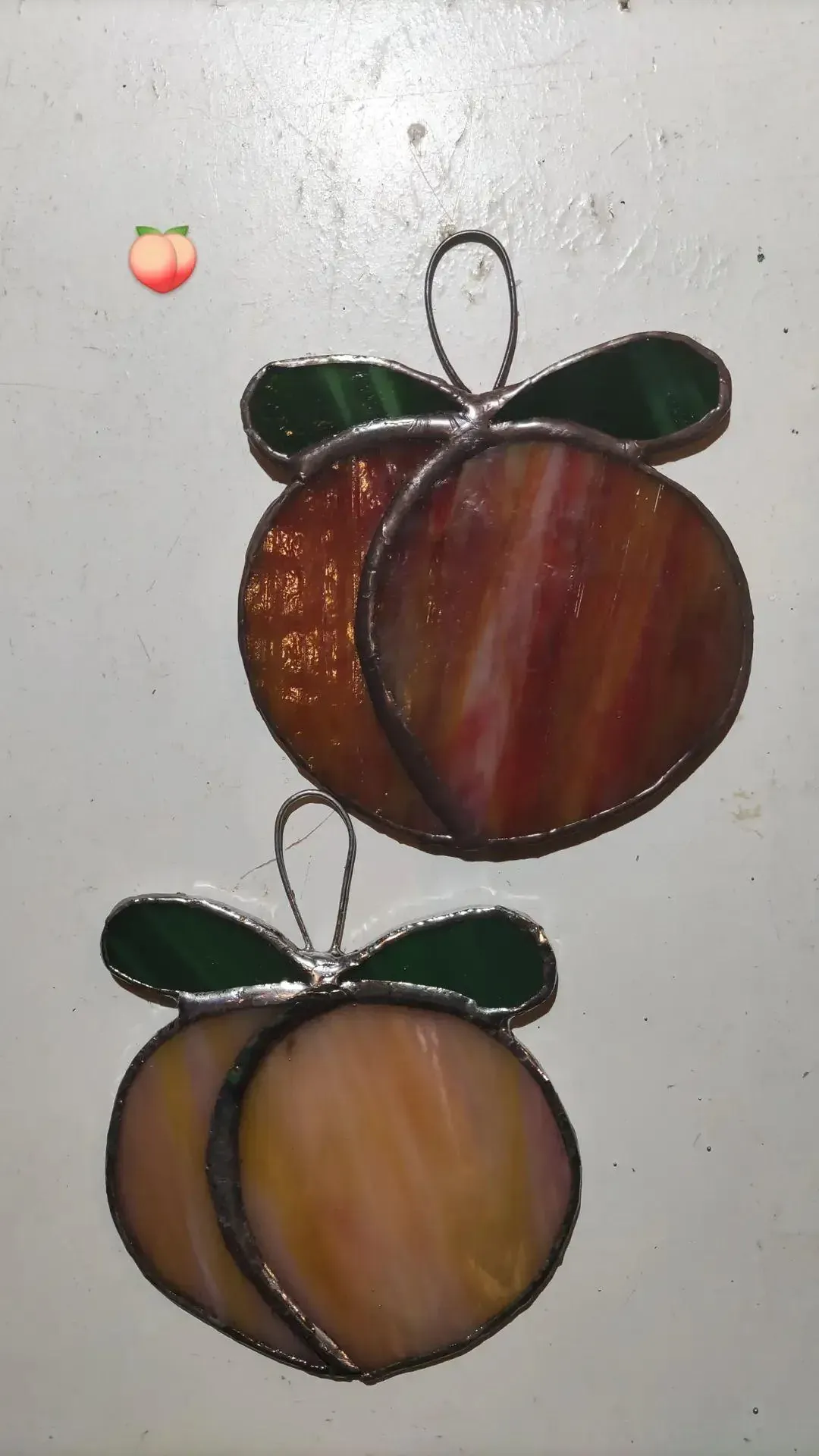 Two peach-shaped stained-glass suncatchers